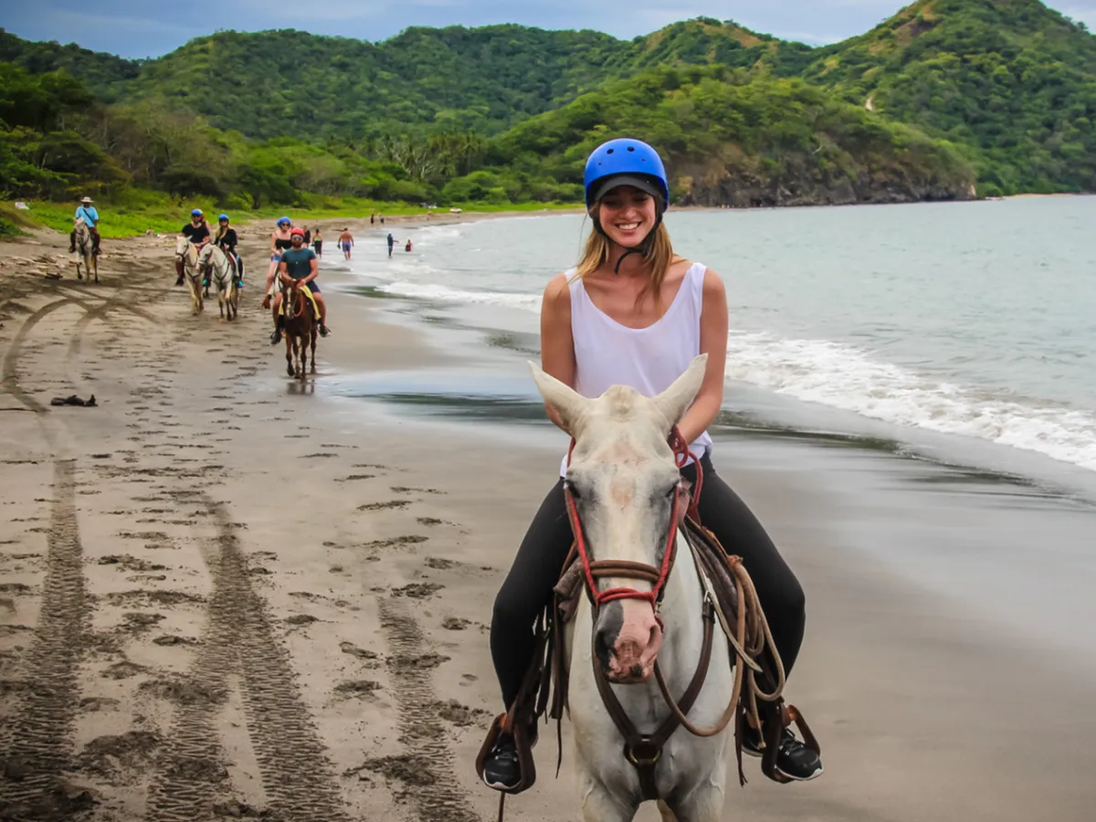 A woman riding a horse on the beach